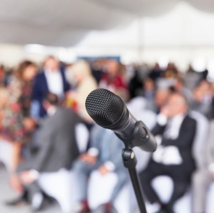 Microphone in focus against blurred audience. Participants at the business or professional conference