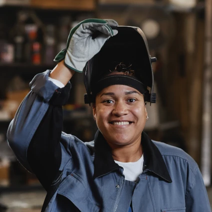 Smiling female welder looking at camera in industrial factory